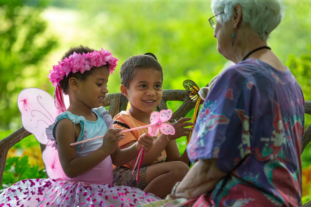 Children dressed as fairies playing with an older woman