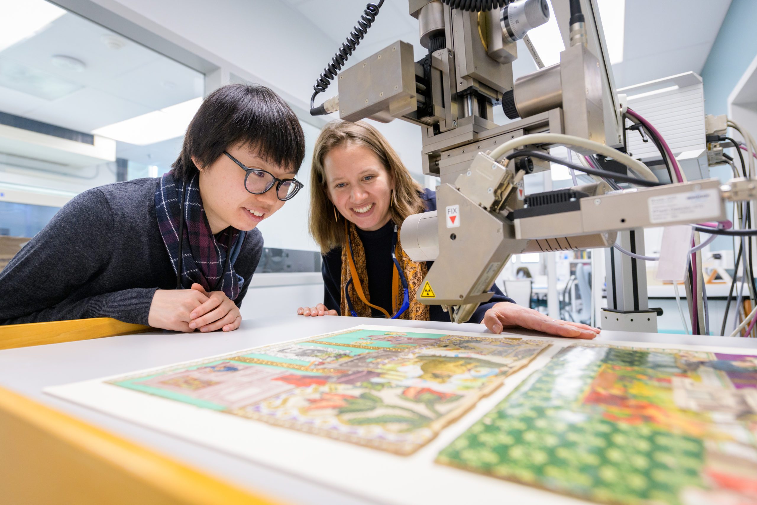 Dr. Rosie Grayburn (right) and graduate student Yan Ling Choi examine the elemental composition of the pigments on “Helen’s Scrapbook House,” using non-destructive X-ray fluorescence  analysis.